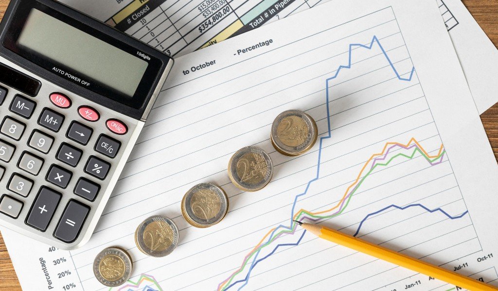 Some coins, pencil, calculator and chart papers on a working desk